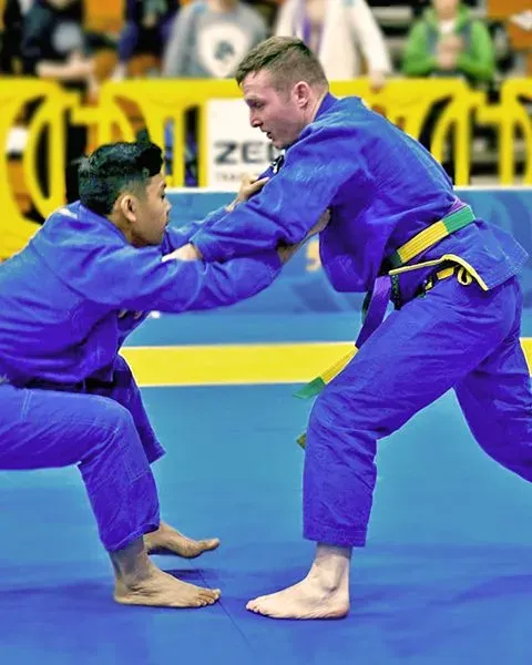 Dr. Steven Dailey, an Orthopedic Surgeon, a white man, competing in a jiu-jitsu match in a blue gi, fighting an opponent.