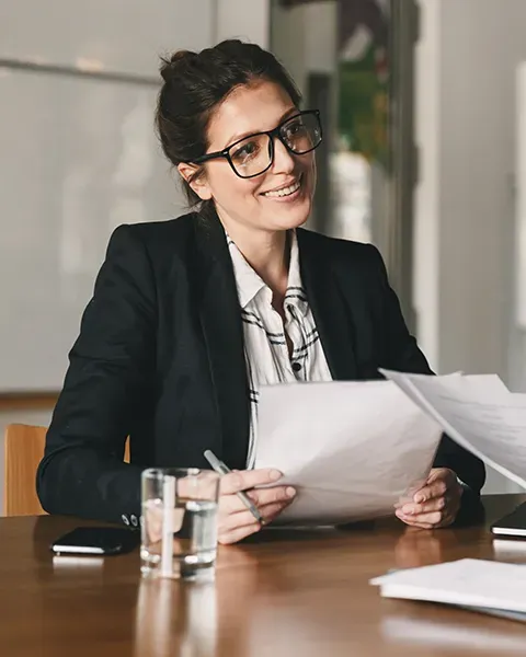 Woman smiling in a meeting with notes in hand