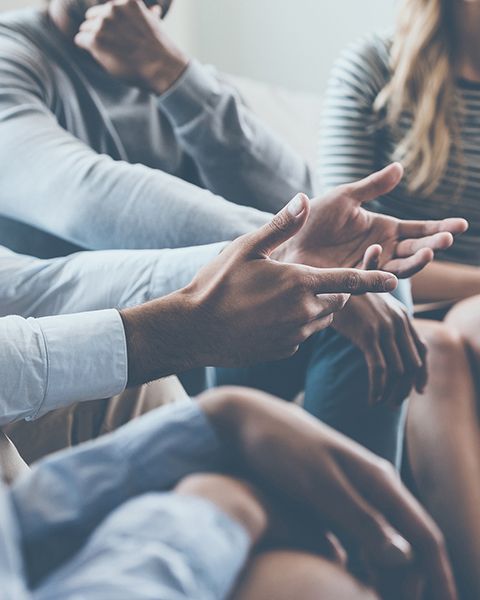 Multiethnic group of people seated in a circle leaning into a constructive conversation. 