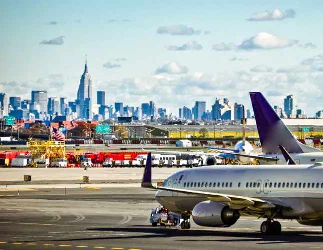 Airplane on runway with Manhattan in the background.