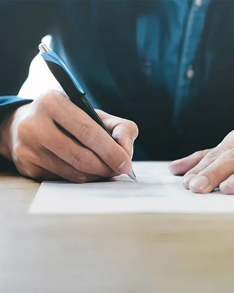 A physician, a white man, in a blue long sleeve collar shirt, a view of his hands holding a contract and reviewing it.