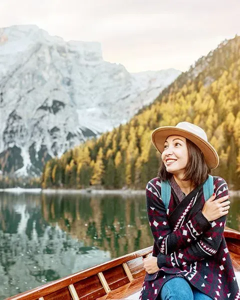 A physician, an Asian woman, on vacation sitting in a small inflatable boat as she overlooks the mountains and lake.