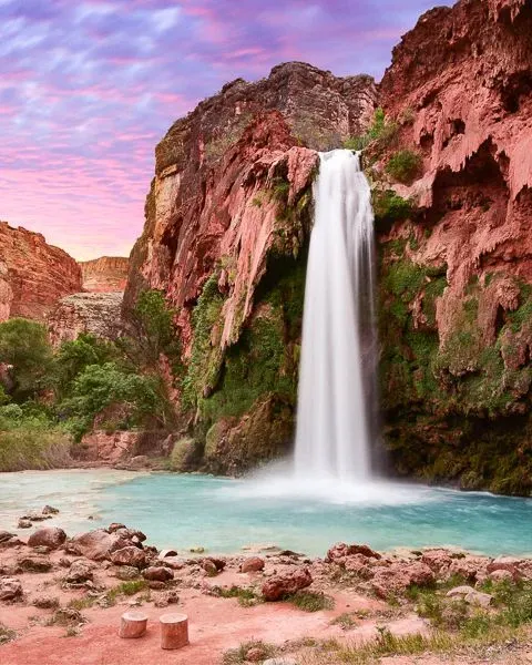 A waterfall in a red rock desert at dusk.
