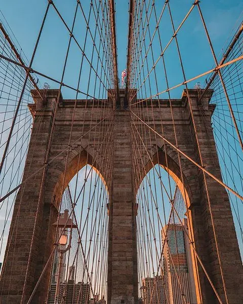 Representing New York is the Brooklyn Bridge in the daytime.