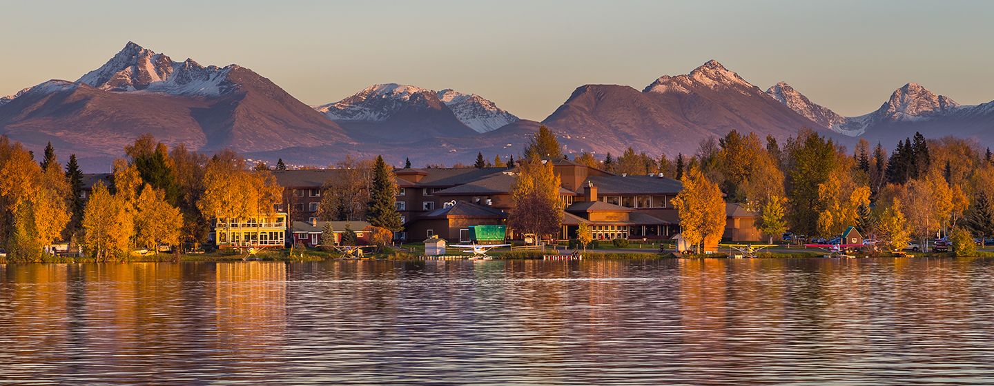 A river at sunset with home and mountains in the background in Anchorage, Alaska.