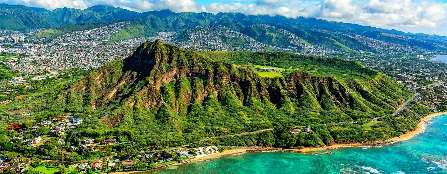 Aerial view of green lush mountains overlooking the ocean in Honolulu, Hawai'i.