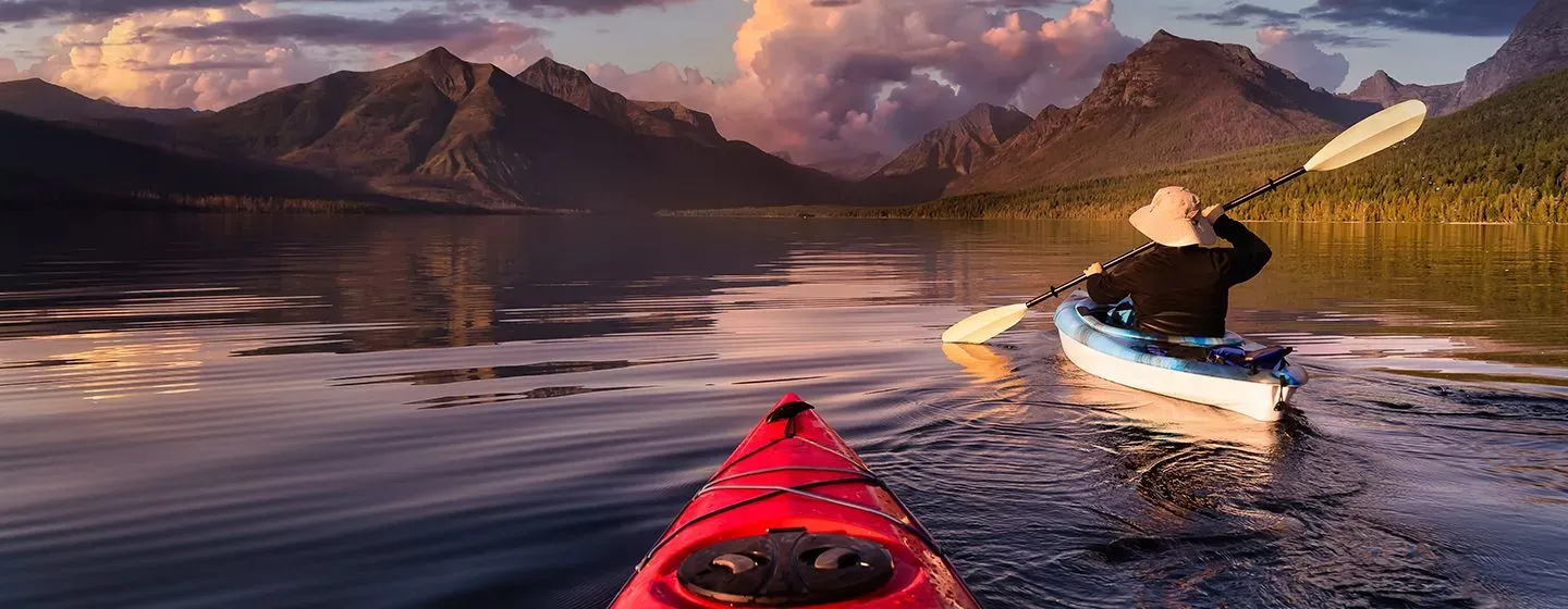 Two kayakers in a river at dusk in Missoula, Montana.