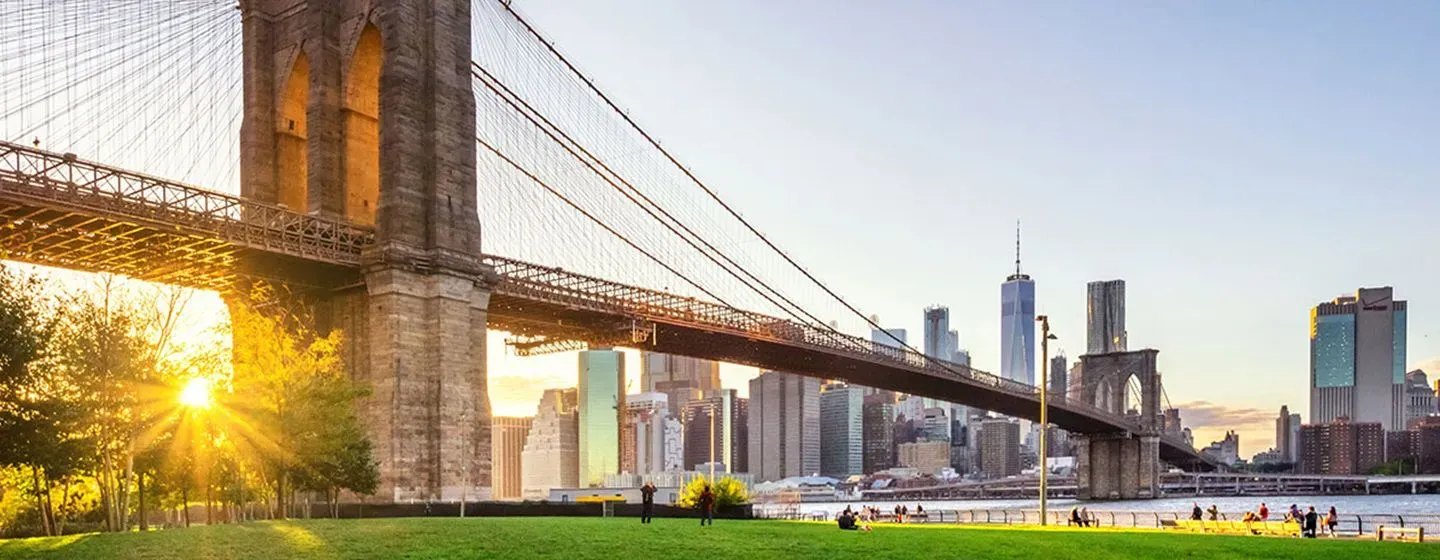 Brooklyn Bridge with a sunset and New York City in the background.