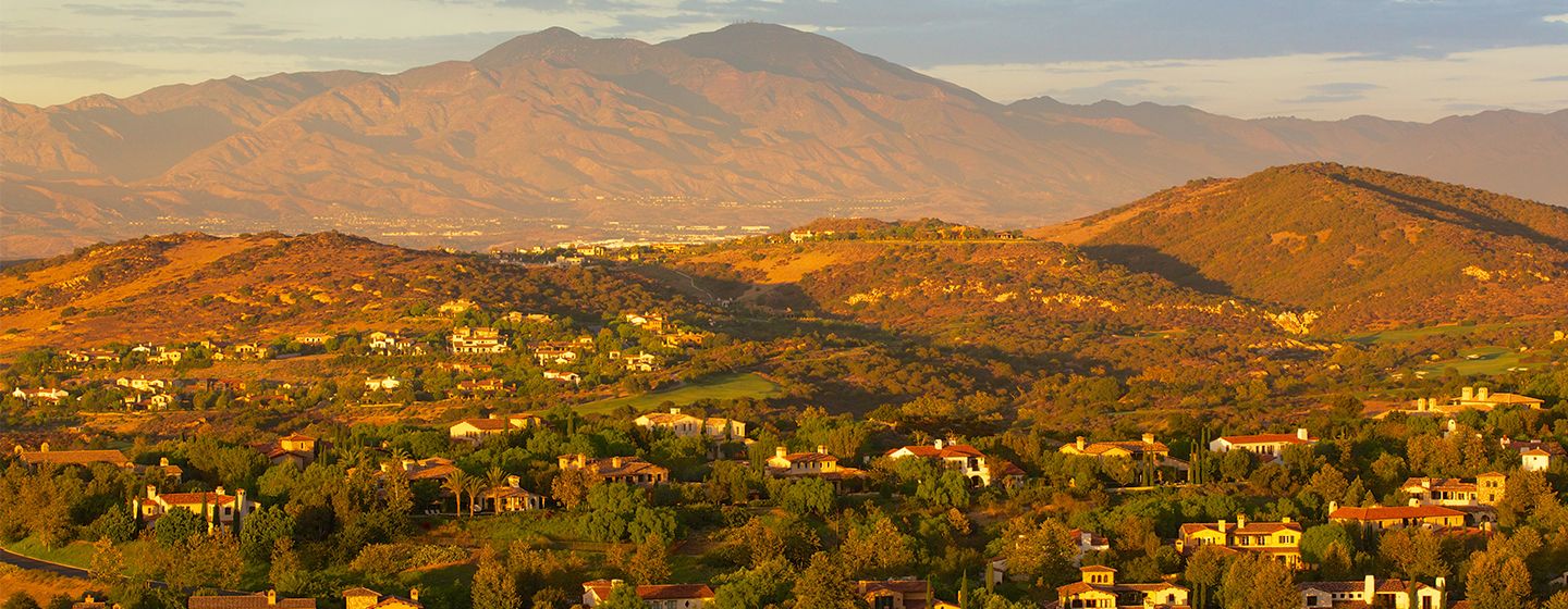 Homes on grassy hills at sunset in Orange, California, aerial view. 