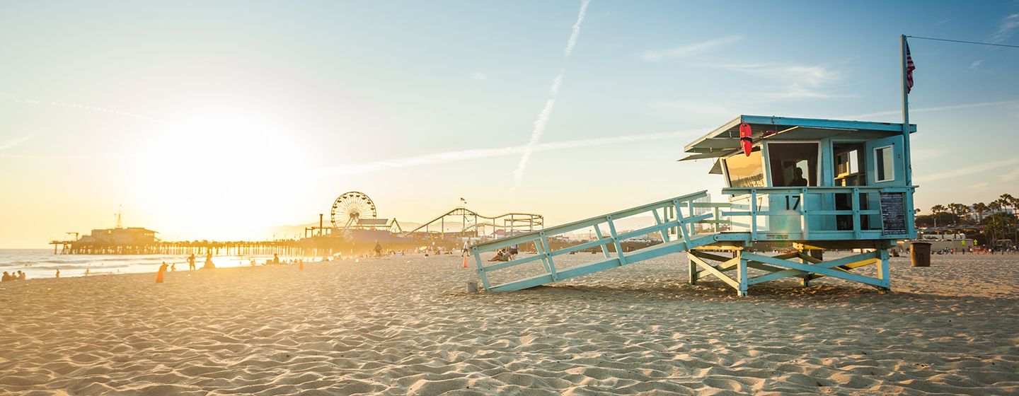 Santa Monica, California beach with pier and ferris wheel in background, at sunset.