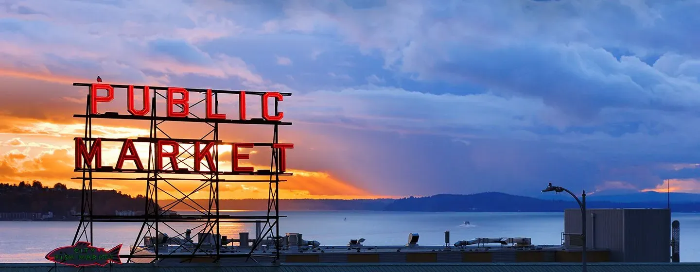 Pike Place's famous sign "Public Market" at sunset with the river in the background in Seattle, Washington.