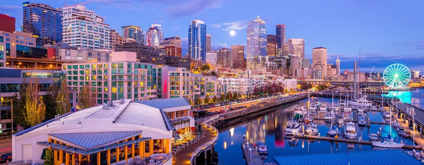 Aerial view of downtown Seattle by the pier at night with ferris wheel and river, in Washington.