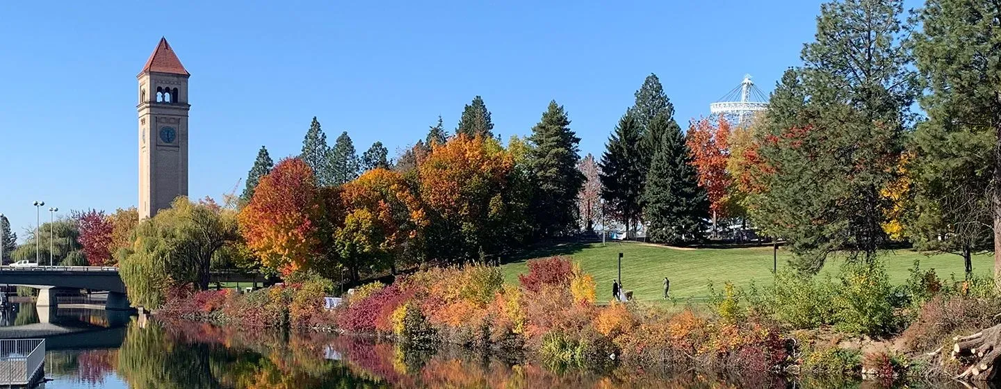 River next to a grassy meadow and park and historical landmark in Spokane, Washington.