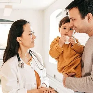 Physician, a Southeast Asian woman, speaking with a father and his child.