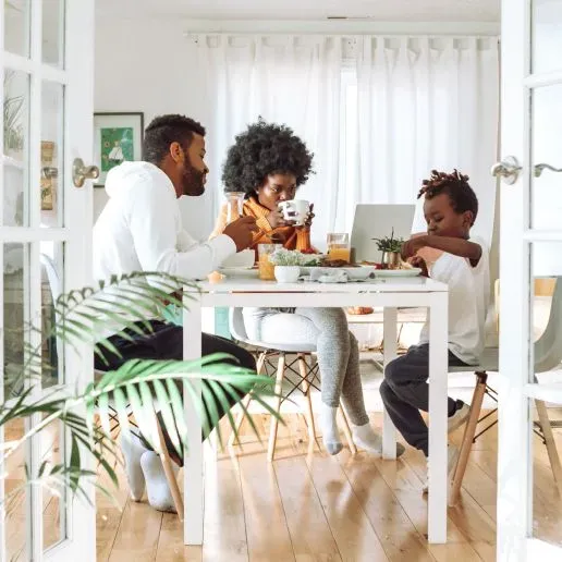 A family, father, mother and young son, at the breakfast table eating and talking, all are Black.