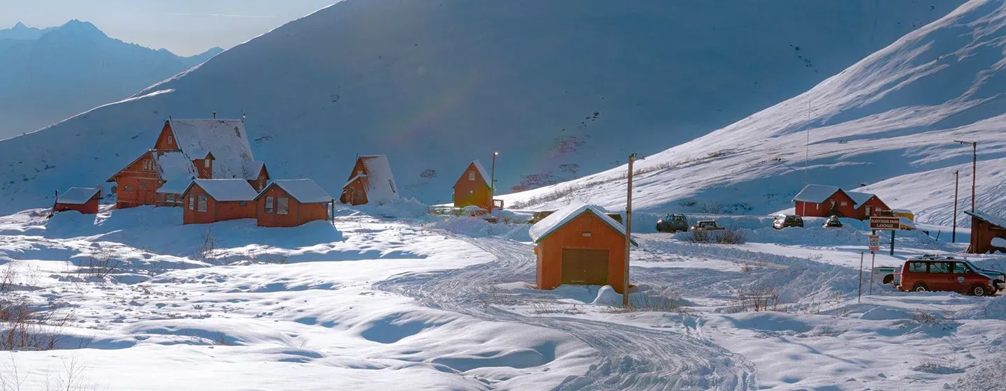 Little red homes at the base of a snowy mountain in Alaska.