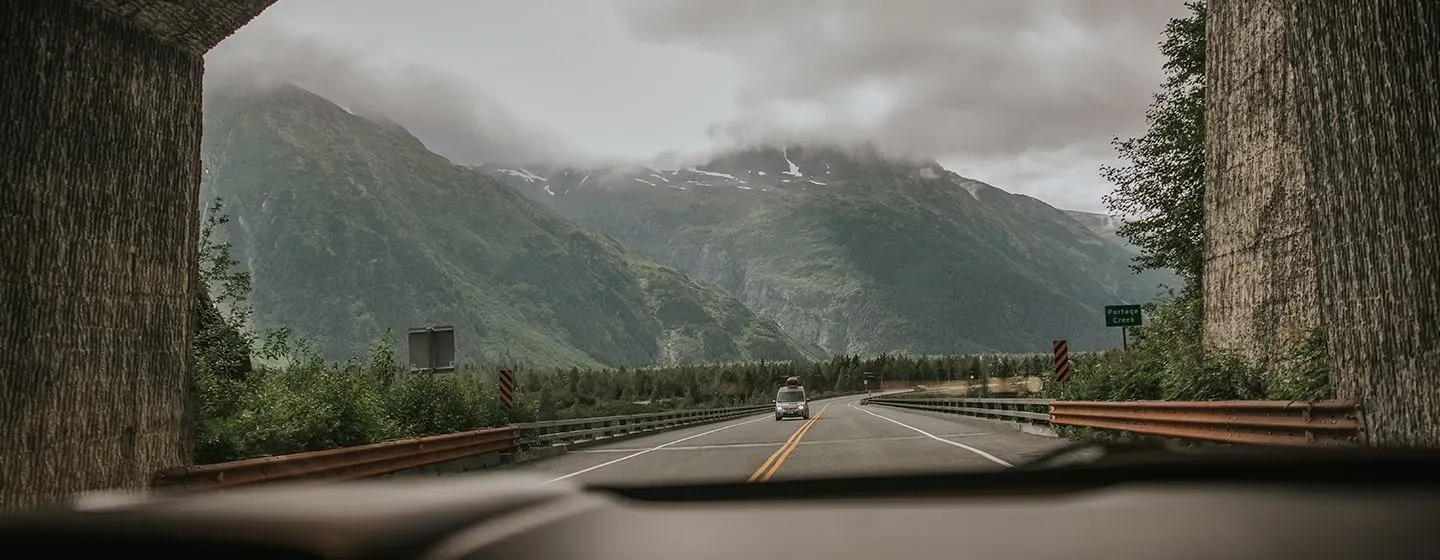 Road tunnel with foggy green mountains in the background in Alaska.