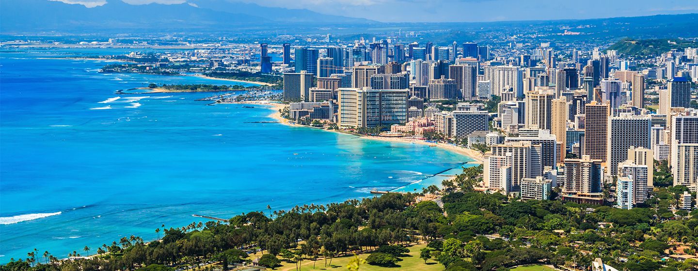 Downtown view of a city in Hawai'i in front of blue shoreline.