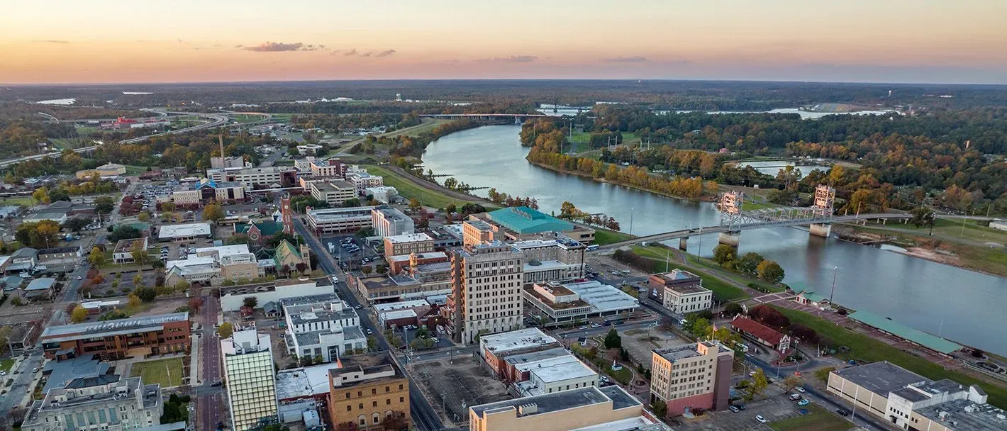 Aerial view of New Orleans with a river, bridge, and buildings at sunset