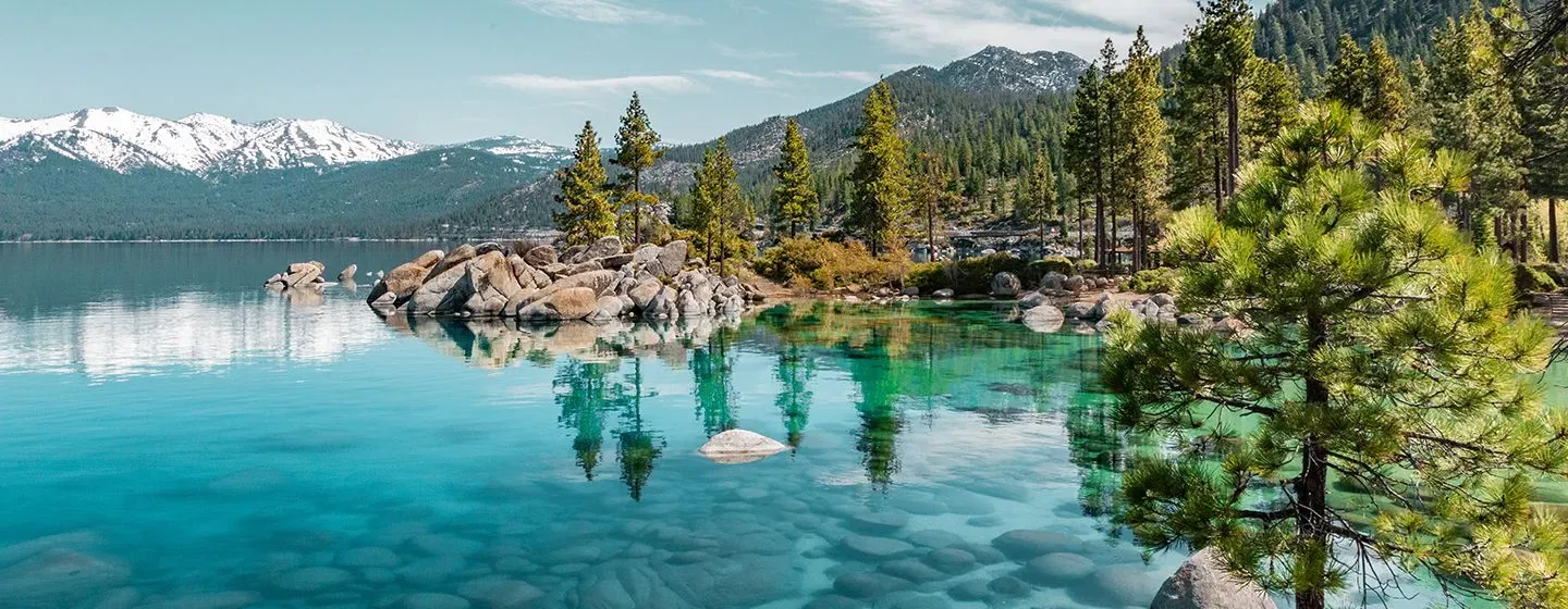 A river with pine trees and snowy mountains around it in the state of Nevada.