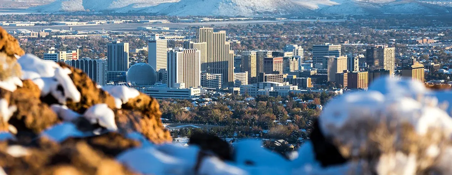 Downtown Reno, Nevada in the daytime with a snowy cliff in the foreground.