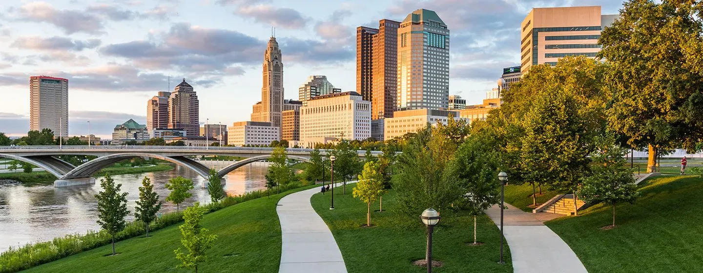 A park next to a river with city buildings in the background in Ohio.