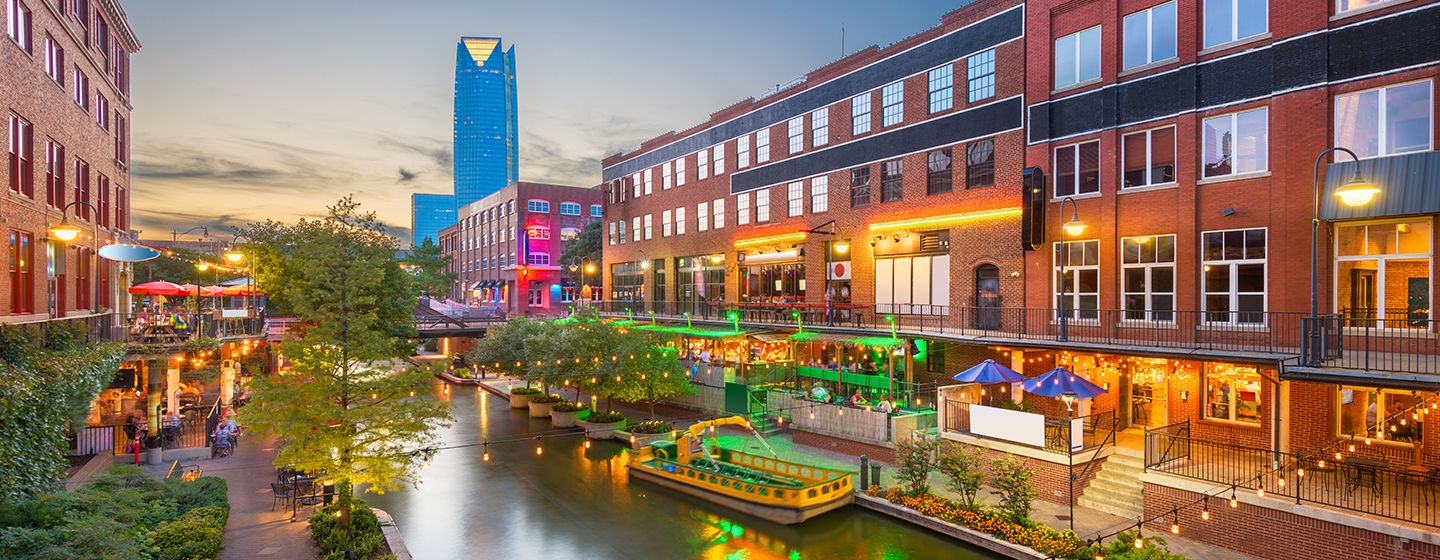 City river with boats surrounded by tall buildings, neon and colorful lights are glowing in Oklahoma.