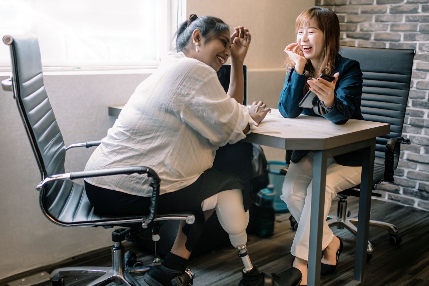 A PS&D recruiter, an Asian woman, with a tablet reviewing jobs with a physician, an Indian woman, with a prosthetic leg.