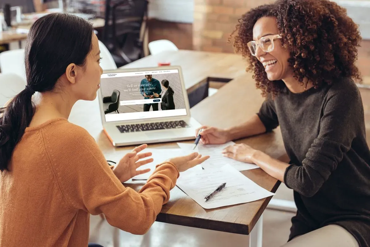 A PS&D recruiter, a Black woman, talking with a client in the medical field, an Asian woman, exploring her career options.