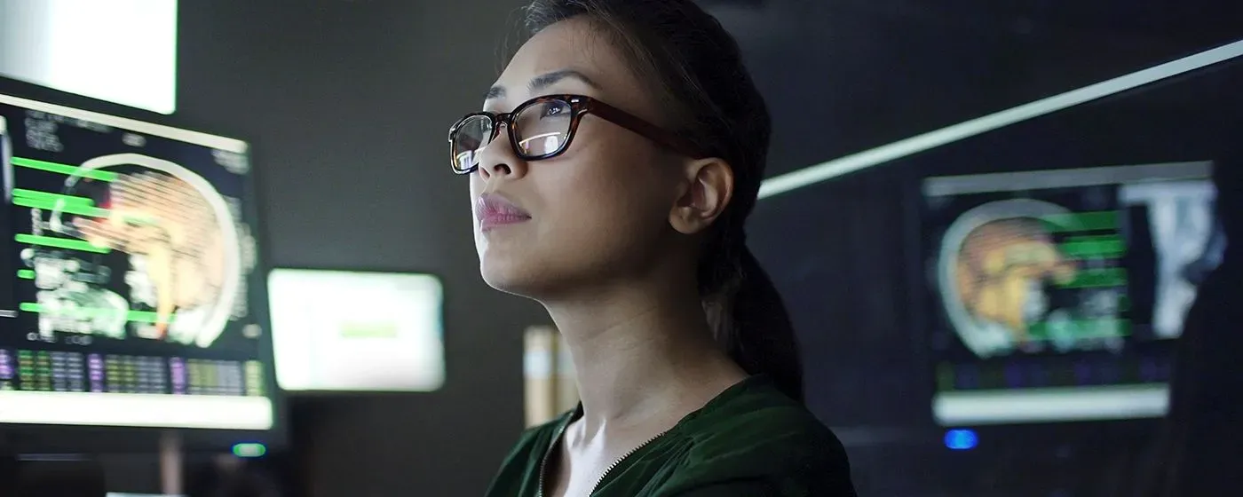 A Neurologist, an Asian woman, in a professional top and glasses, reviewing brain scans.